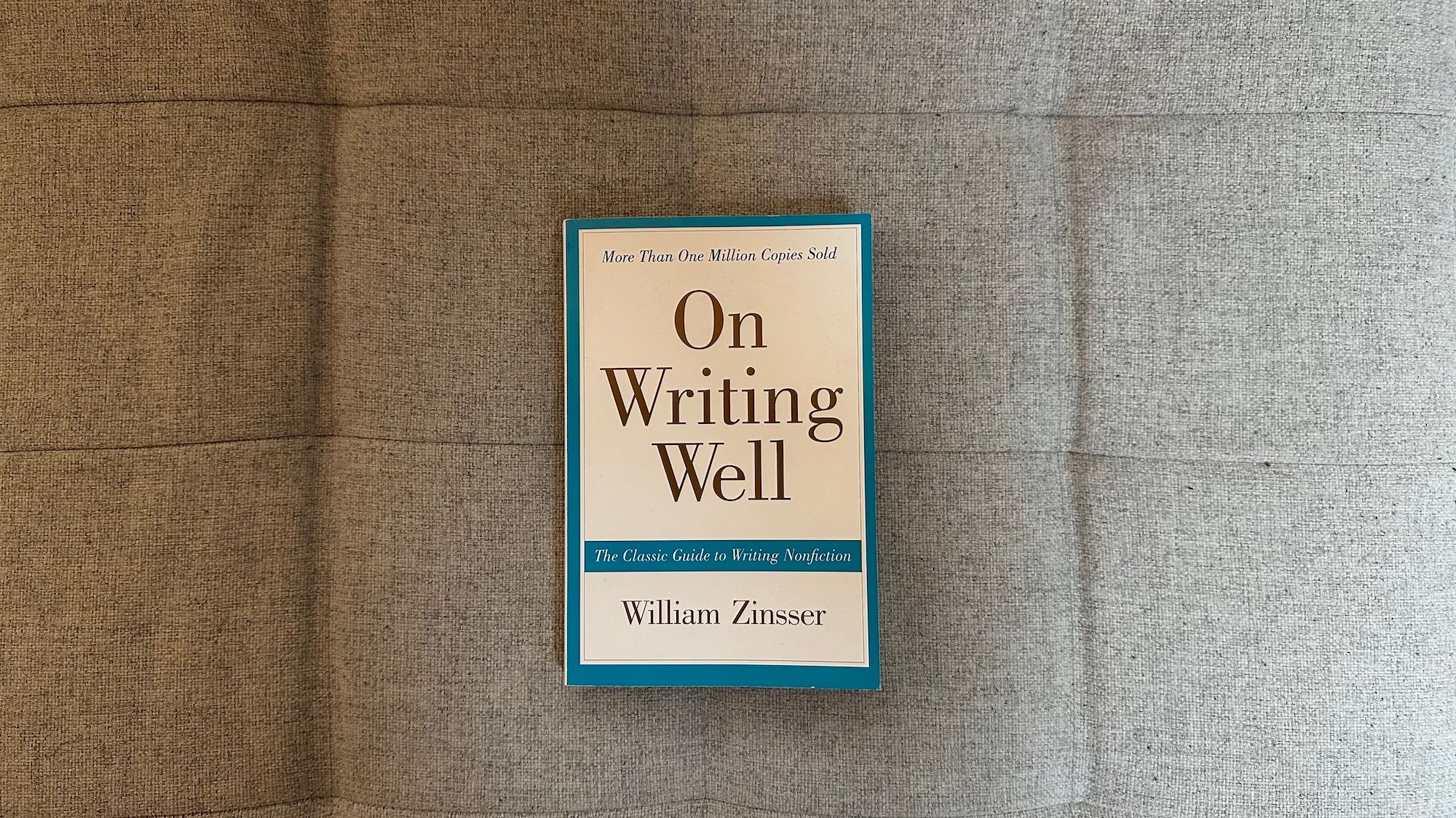 Book "On Writing Well" by William Zinsser laying on my couch.