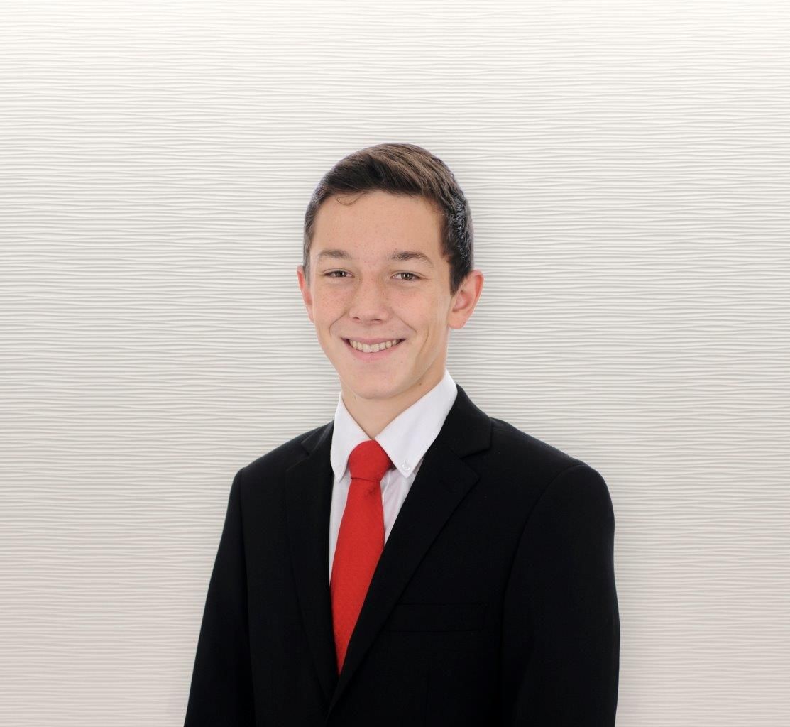Image of me at 16 years old wearing a black suit and red tie. I look like a child.